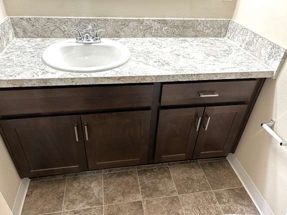 Bathroom vanity with granite countertop and dark cabinetry at Heatherwood Apartments, Grand Blanc