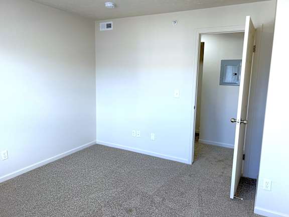 Empty carpeted bedroom with doorway to hallway at Heatherwood Apartments, Grand Blanc, MI 48439