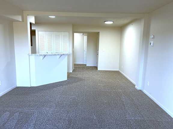 Open living space with kitchen bar and hallway at Heatherwood Apartments, Grand Blanc, 48439