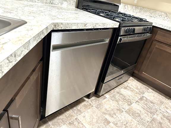 Stainless steel dishwasher and gas range corner at Heatherwood Apartments, Michigan