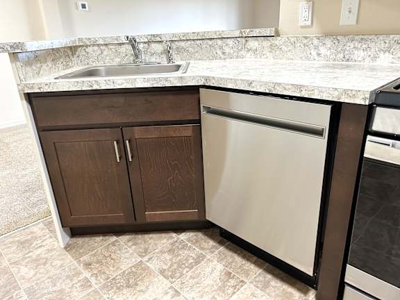A kitchen with a granite countertop and a dishwasher.