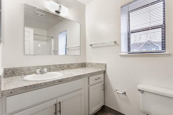 A white bathroom with a sink, mirror, and tub