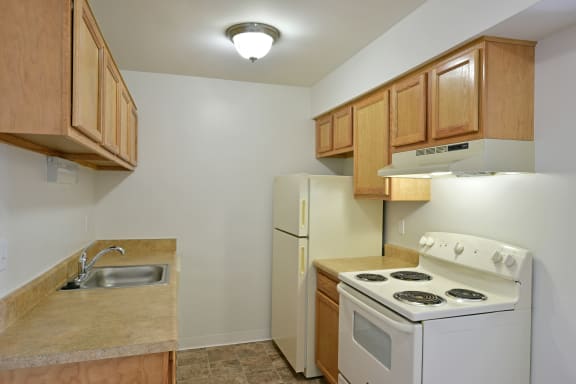 a kitchen with a stove refrigerator and sink at Charter Oaks Apartments, Davison, MI