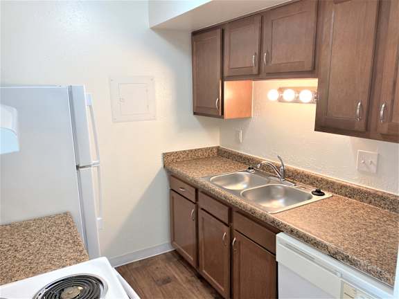 A kitchen with a white fridge, brown cabinets, and a granite countertop.