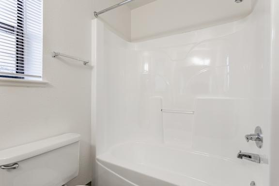 A white bathroom with a tub, shower, and toilet