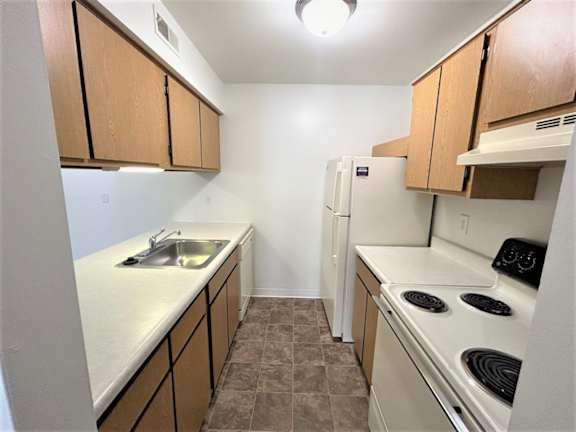 Galley kitchen with electric stove and refrigerator 1 at Charter Oaks Apartments, Davison, Michigan