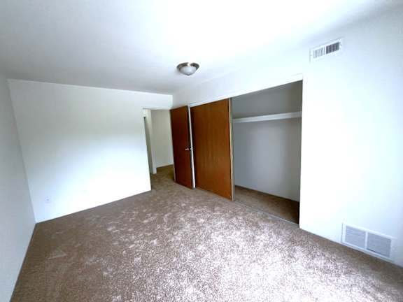 Carpeted bedroom with large open closet space at Charter Oaks Apartments, Michigan, 48423