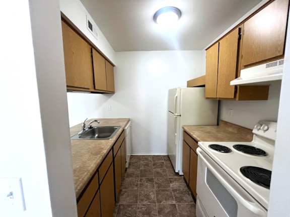 Galley kitchen with white appliances and laminate countertops at Charter Oaks Apartments, Davison, MI, 48423