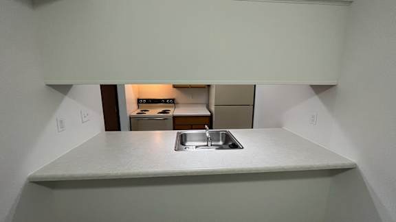 Kitchen pass through with sink and view of stove at Charter Oaks Apartments, Davison, MI