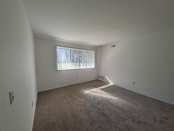 Bright carpeted bedroom with horizontal blinds and heating vent at Charter Oaks Apartments, Davison