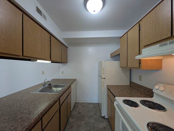 Narrow galley kitchen with electric range and overhead cabinets at Charter Oaks Apartments, Michigan
