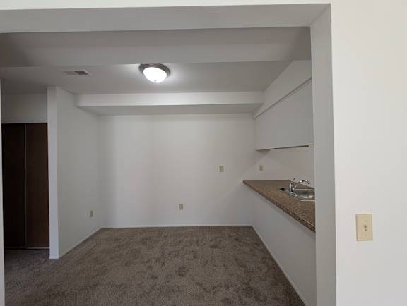 Carpeted basement room with wet bar and ceiling lighting at Charter Oaks Apartments, Davison, MI