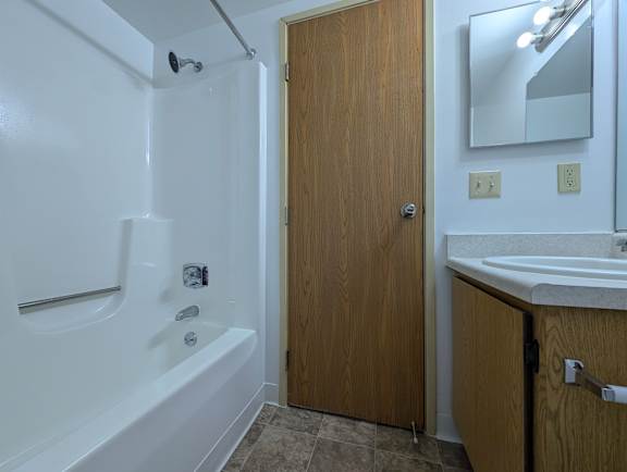 Bathroom with tub shower and oak vanity cabinet at Charter Oaks Apartments, Davison, Michigan