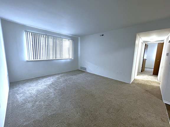 Spacious carpeted room with window and hallway at Charter Oaks Apartments, Michigan, 48423