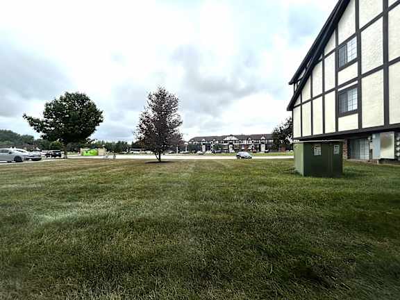 Tudor style building exterior with open lawn area at Charter Oaks Apartments, Davison