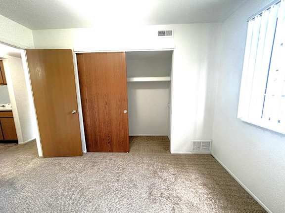 Carpeted bedroom with open closet and sliding doors at Charter Oaks Apartments, Michigan