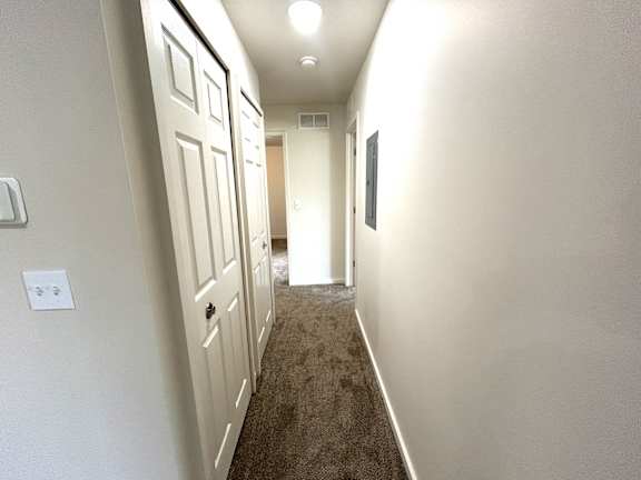 Hallway with carpet and white walls.