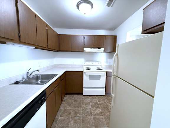 A kitchen with a white refrigerator, sink, and stove.