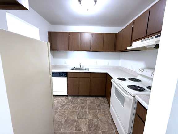A kitchen with brown cabinets and a white stove top oven.