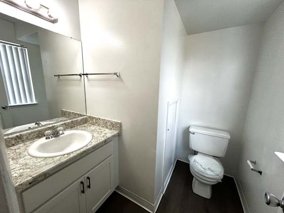 A bathroom with a toilet, sink, and mirror.