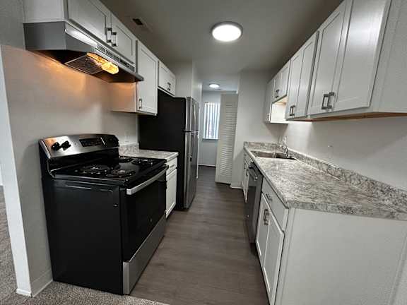 A kitchen with black appliances and white cabinets.