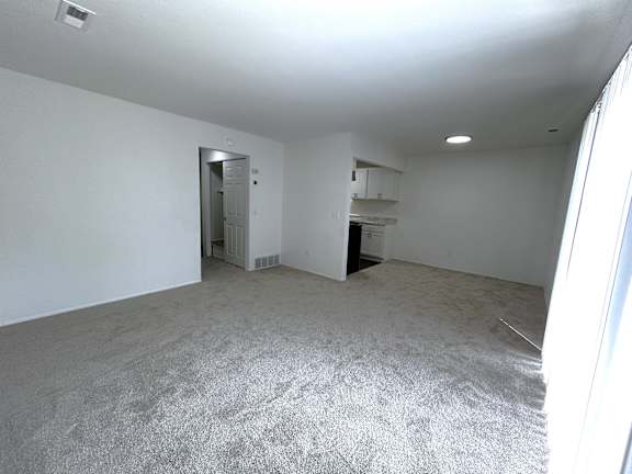 A living room with a carpeted floor and a door leading to another room.