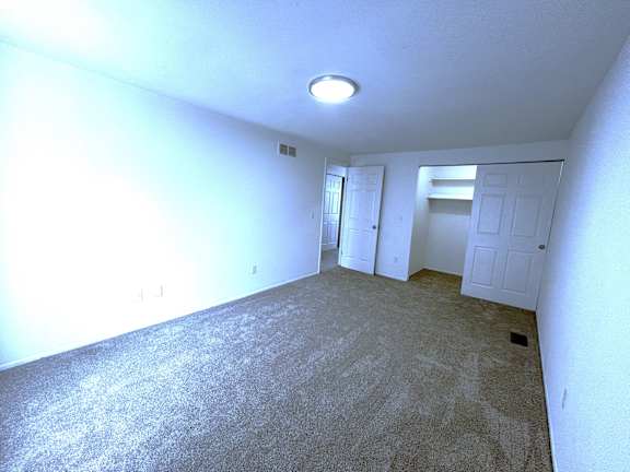 A  bedroom with a carpeted floor and a ceiling light.