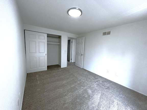 A bedroom with a carpeted floor and a ceiling light.