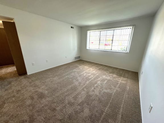Sunlit carpeted bedroom with large window and blinds at Charter Oaks Apartments, Davison, 48423