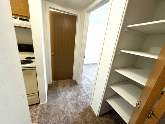 Hallway with pantry closet and brown wood door at Charter Oaks Apartments, Davison