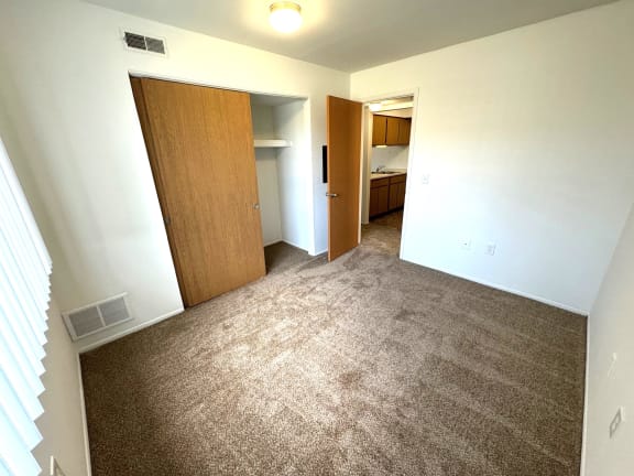 Empty bedroom with open closet and doorway to kitchen at Charter Oaks Apartments, Michigan