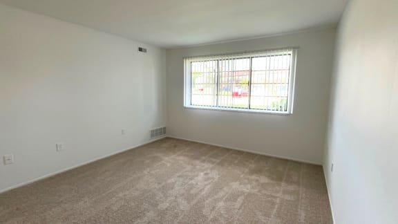 Empty carpeted bedroom with window and bright natural light at Charter Oaks Apartments, Davison, MI