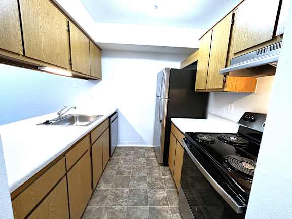 Galley kitchen with oak cabinets and black appliances at Charter Oaks Apartments, Davison, 48423