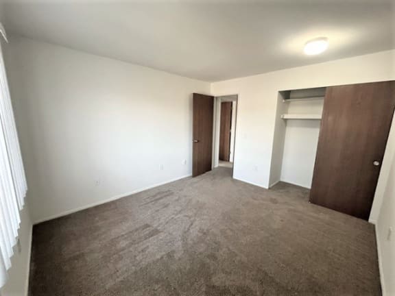 Empty carpeted bedroom with closet and brown doors at Charter Oaks Apartments, Davison, MI
