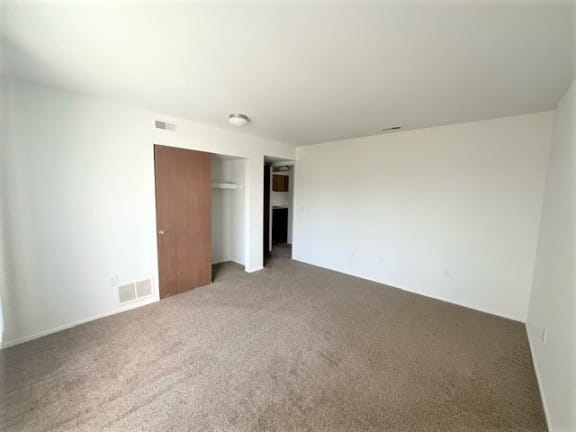 an empty living room with white walls and a door at Charter Oaks Apartments, Davison