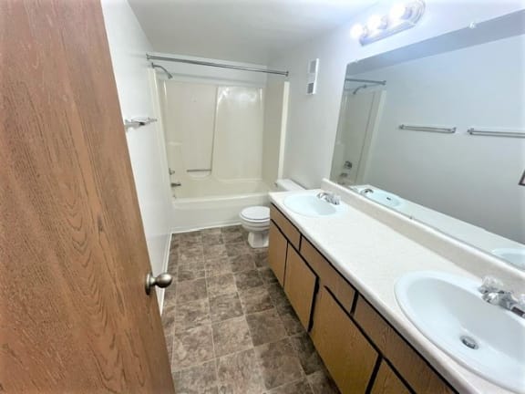 an empty bathroom with two sinks and a toilet at Charter Oaks Apartments, Davison
