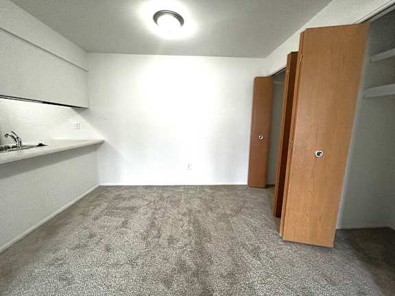 Carpeted room with closet and compact kitchenette at Charter Oaks Apartments, Davison, Michigan
