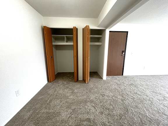 Empty carpeted room with two open closets at Charter Oaks Apartments, Michigan
