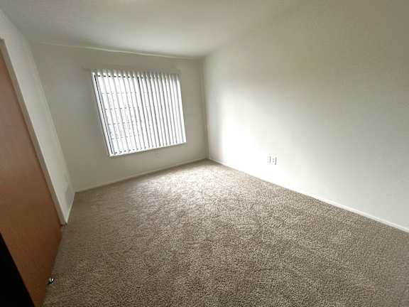 Empty carpeted room with window and vertical blinds 4 at Charter Oaks Apartments, Michigan