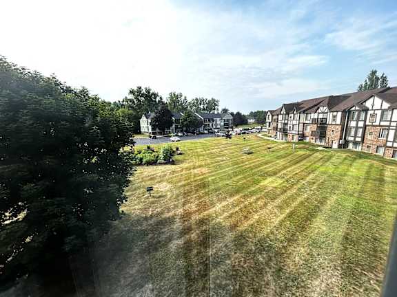 Freshly mowed lawn with residential buildings and parking area at Charter Oaks Apartments, Michigan