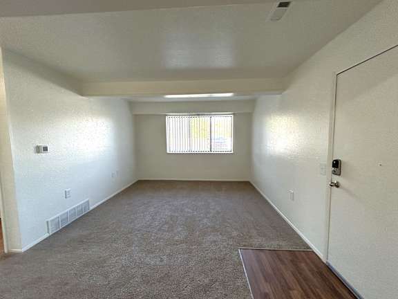 A spacious living room with a window and a door.
