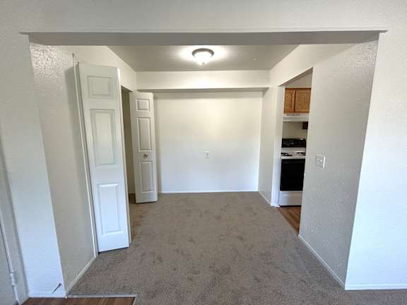 A dining room with a carpeted floor and a white door.
