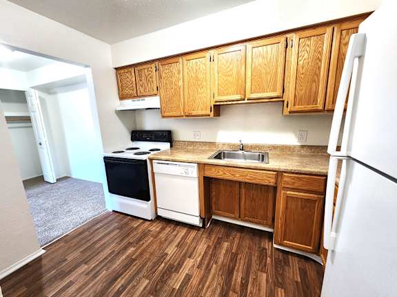 A kitchen with wooden cabinets and a white fridge.