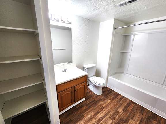 A white bathroom with wood flooring and a walk-in shower.