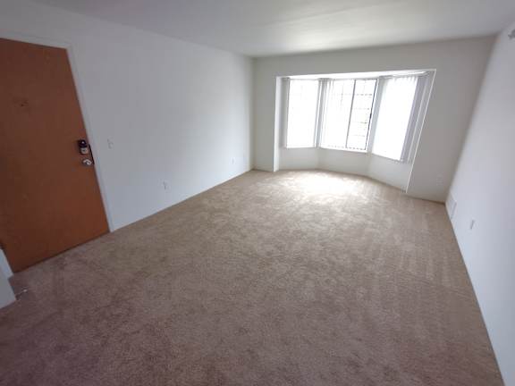 Bright carpeted living room with bay window at Charter Oaks Apartments, Davison, MI, 48423