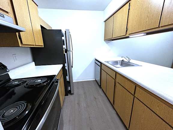 Galley kitchen with coil stove and oak cabinets at Charter Oaks Apartments, Davison