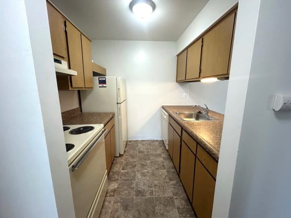 Galley kitchen with white appliances and granite countertops at Charter Oaks Apartments, Davison, MI, 48423