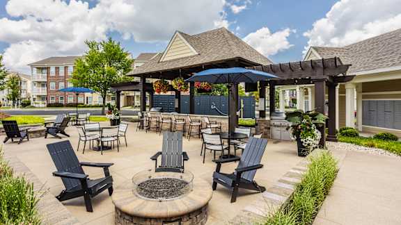 A patio with a fire pit and chairs.