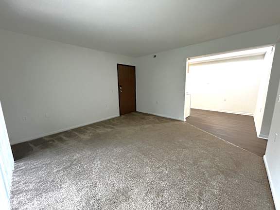 A living room with a carpeted floor and a door.