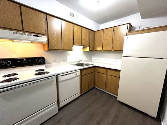 A kitchen with white appliances and wooden cabinets.